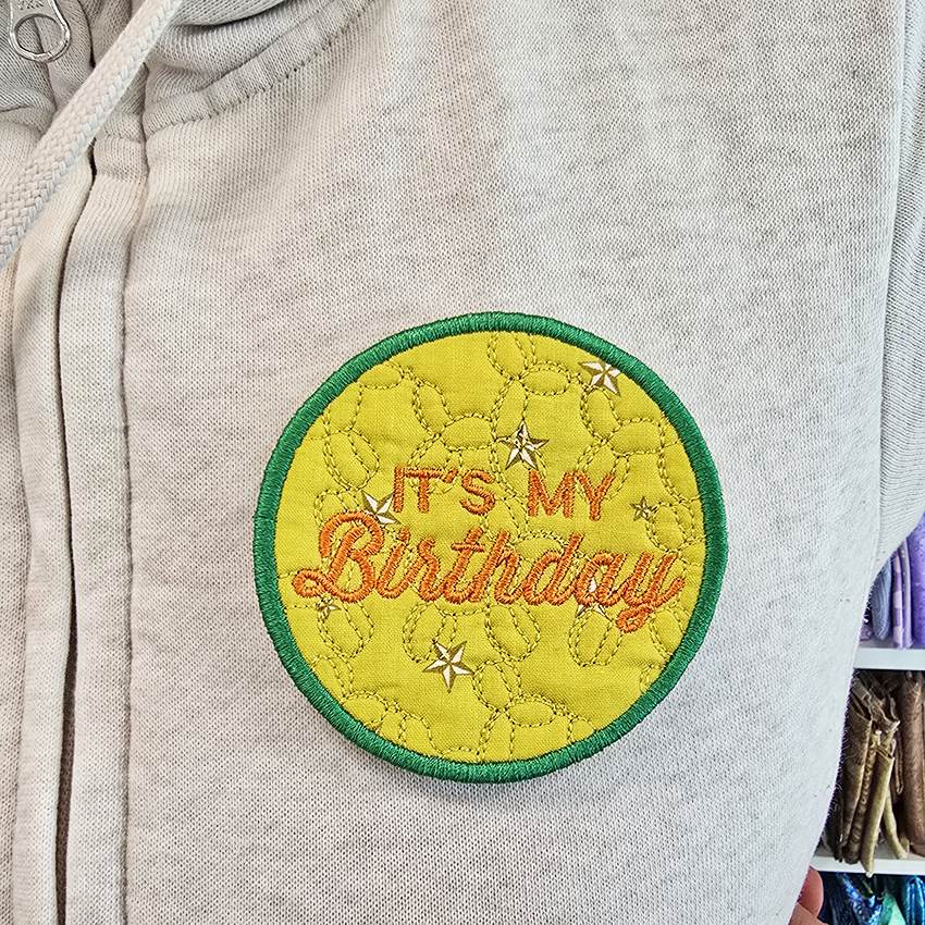 Embroidered patch on a gray hoodie with 'It's My Birthday' text
