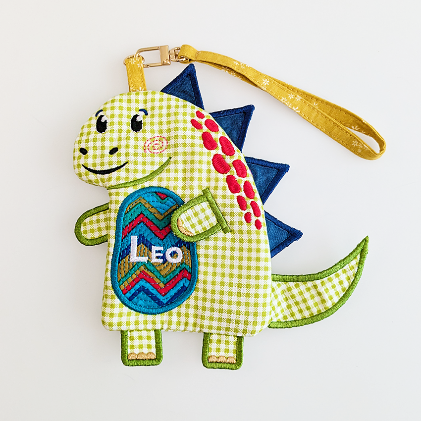 green dinosaur purse with blue spikes and custom text on belly in bigger size with wrist strap