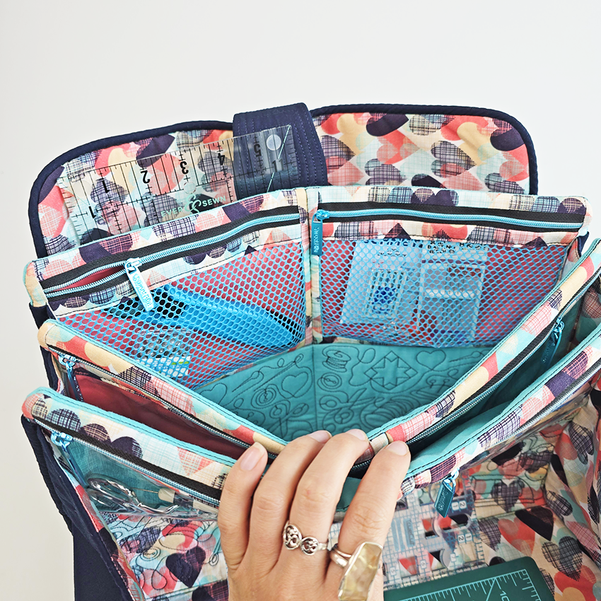 Colorful craft bag with multiple compartments held open by a hand.