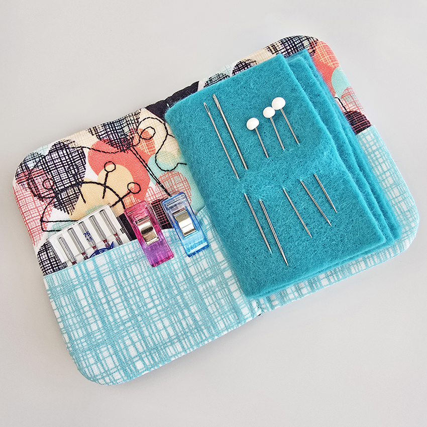 needle book open with needles, pins, and clips