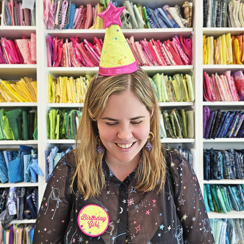 Woman wearing a colorful party hat and a birthday girl badge made by sweet pea