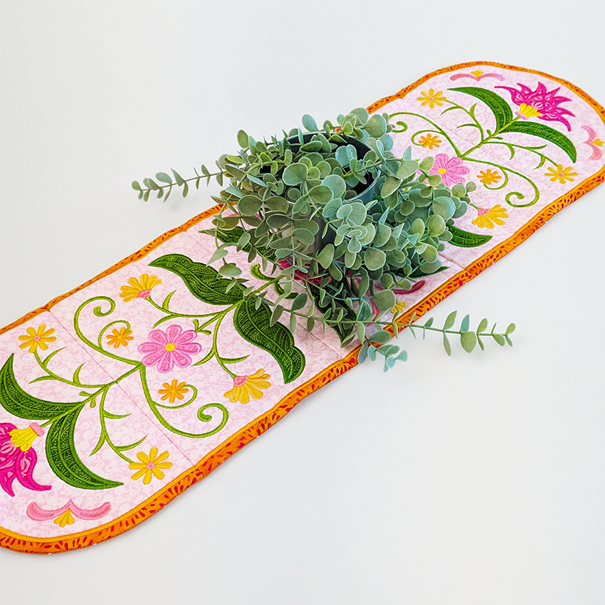 Floral embroidered table runner styled with a plant