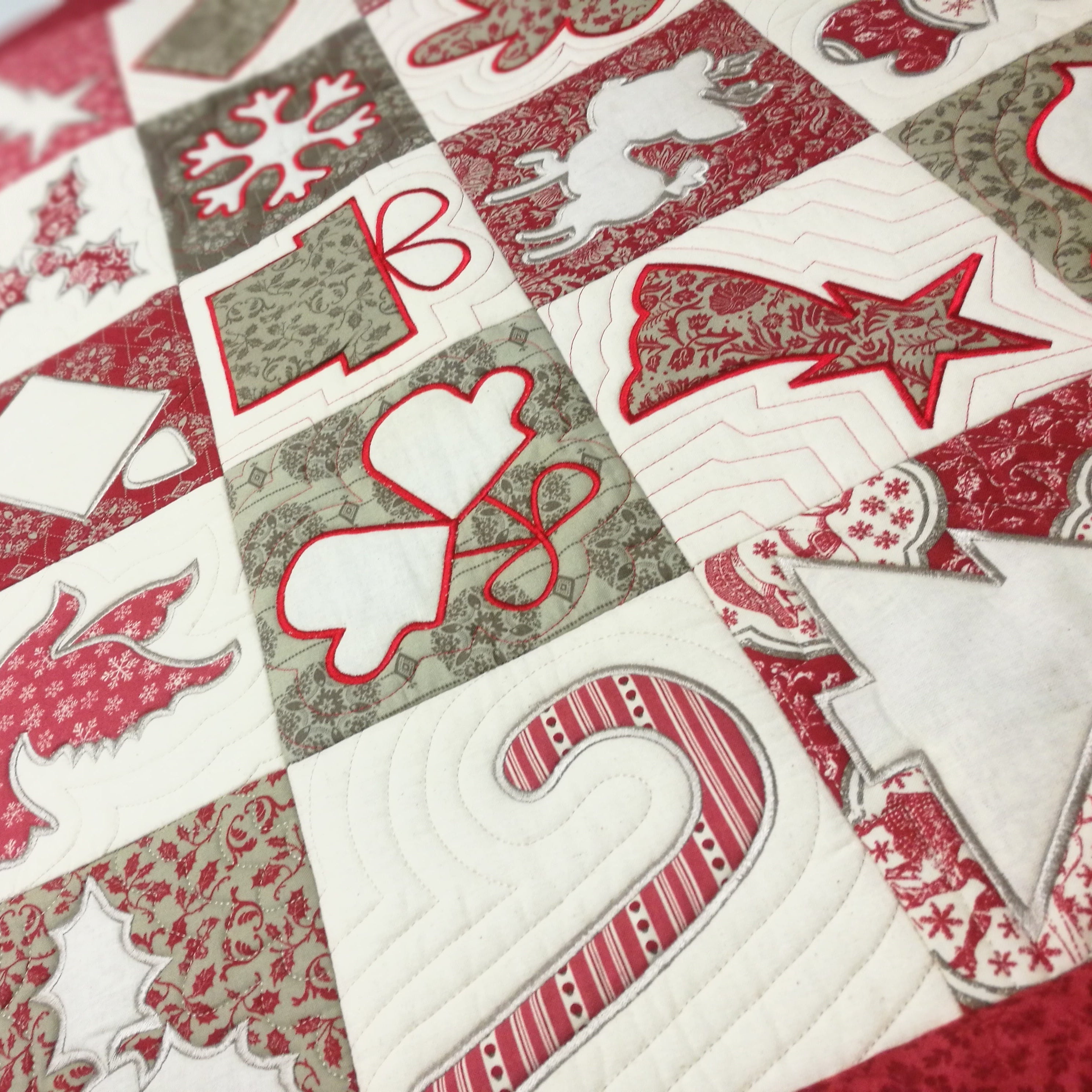 Close-up of a quilt with Christmas-themed patterns similar to cookie cutter shapes