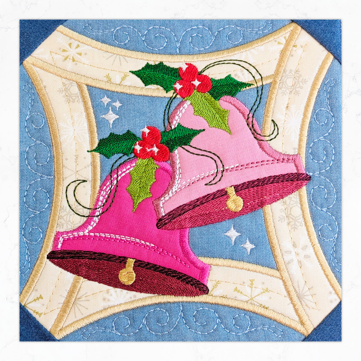 An embroidered Christmas quilt design featuring two pink bells with red berries and green holly leaves, SP Christmas BOW 2026