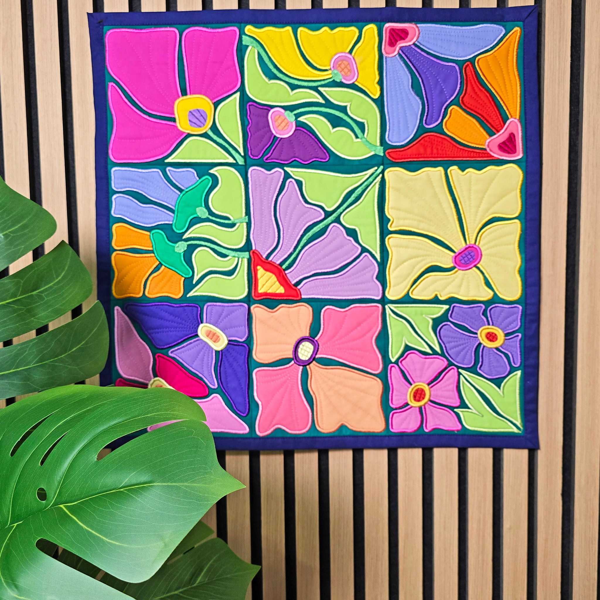 Colorful floral ITH quilt with a plant in the foreground