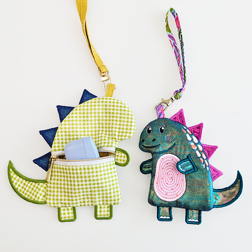 green dinosaur purse with blue spikes and custom text on belly  in bigger size from the back with smaller shiny dinosaur next to it