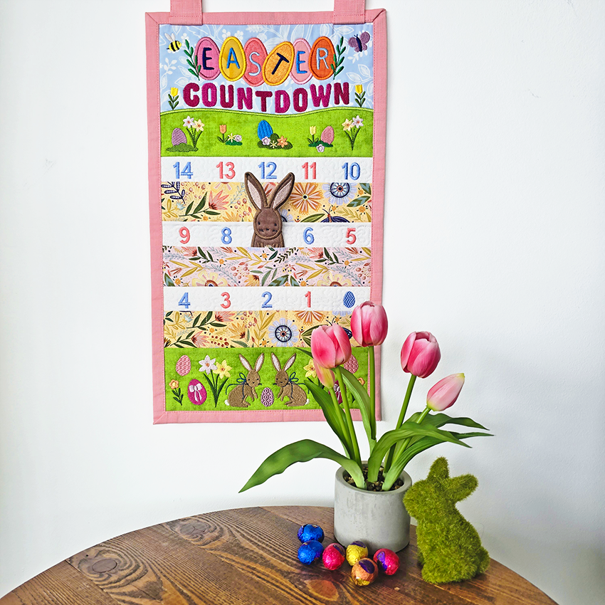 Easter countdown calendar with pink border, tulips, and Easter decorations on a wooden table.