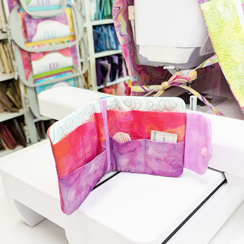Colorful fabric wallet on a table with sewing machine and materials in the background