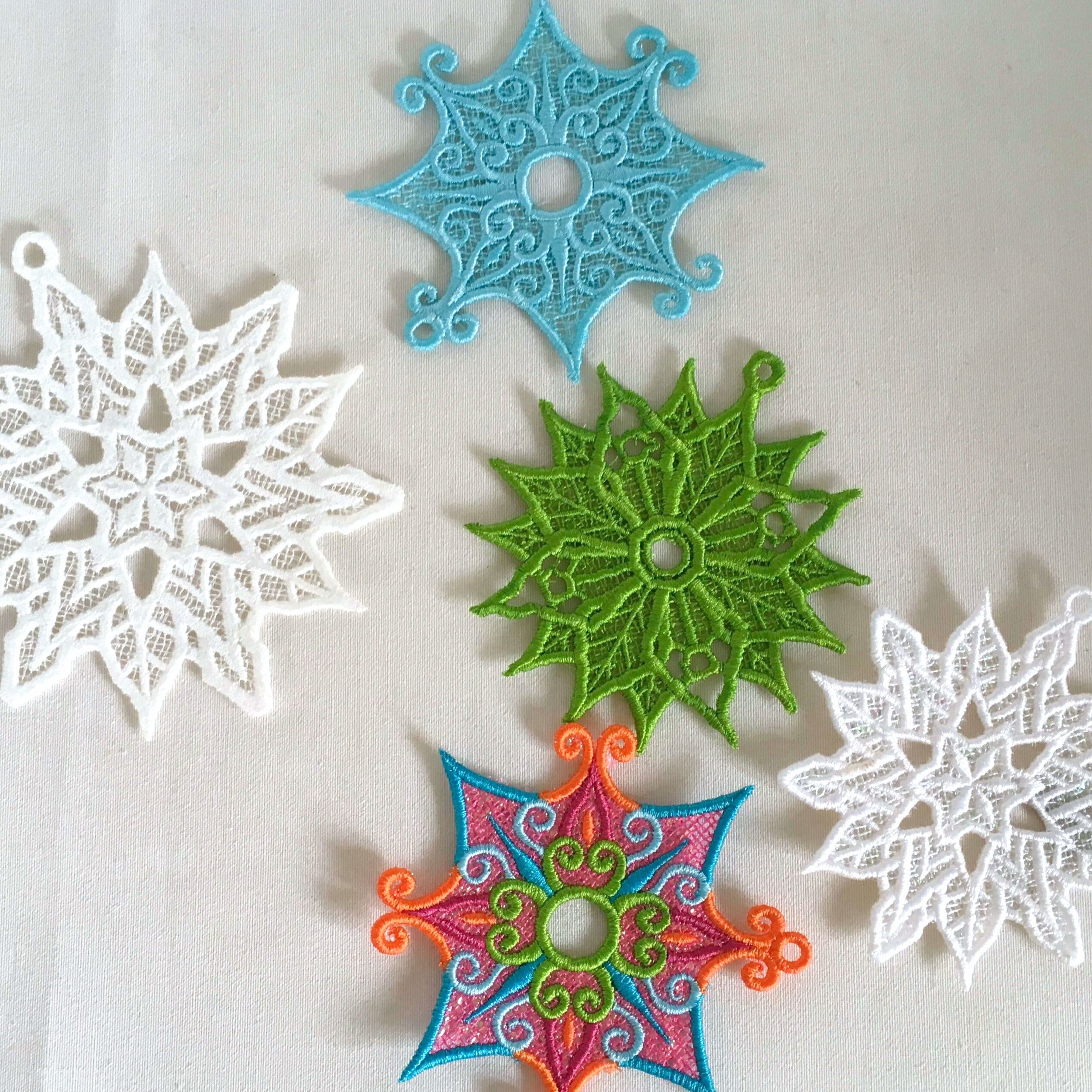 Colorful snowflake-shaped FSL decorations made in the hoop by sweet pea