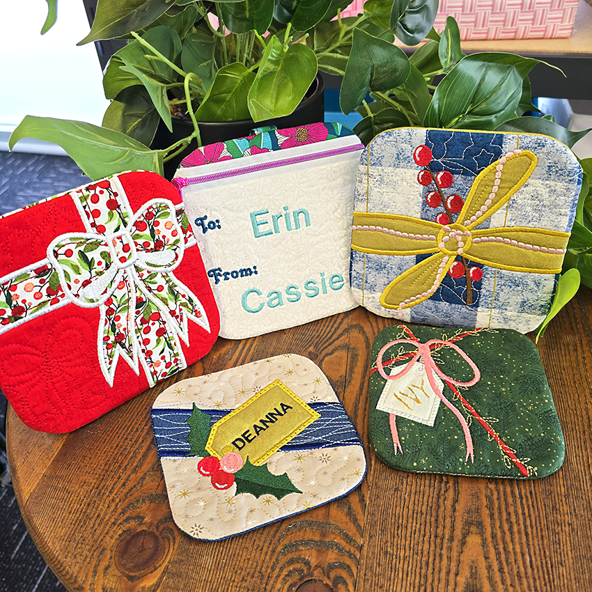 Decorative ITH gift bags and coasters with personalized names on a wooden surface with plants in the background