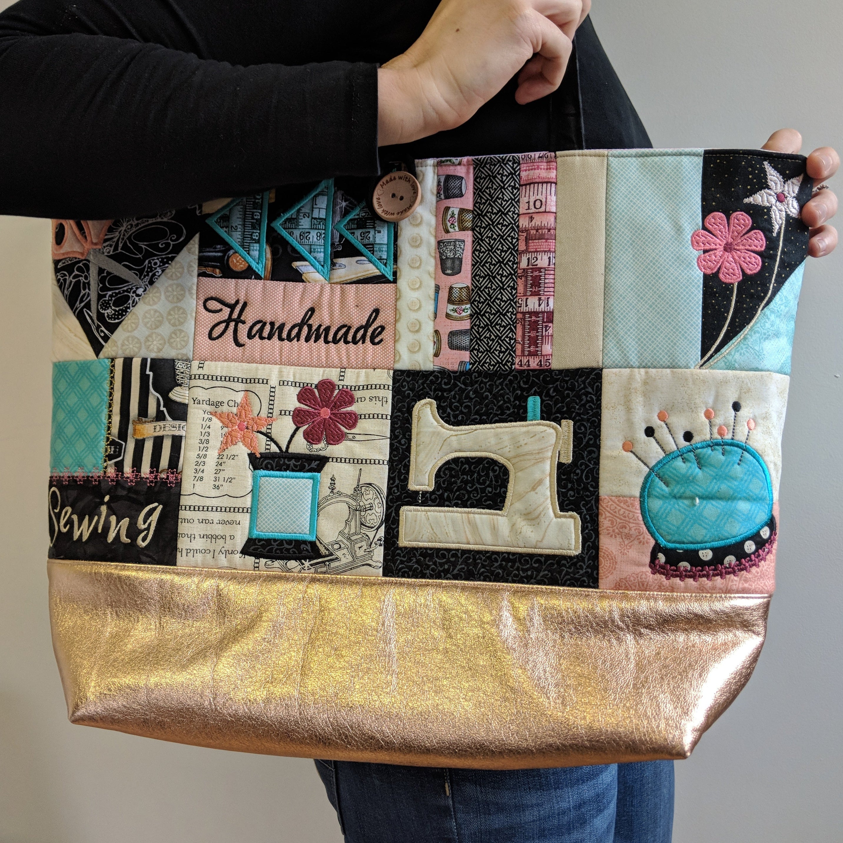 Person holding a patchwork tote bag with sewing-themed designs.