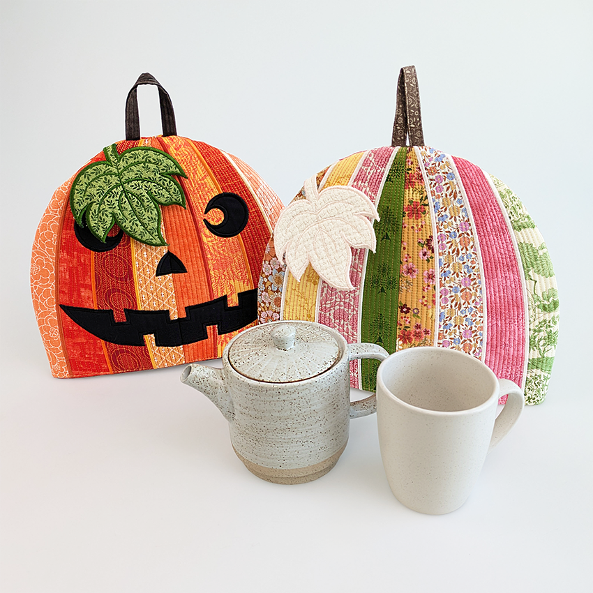 Two embroidered pumpkin designs with a teapot and mug 