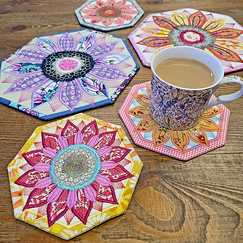 Colourful hexagonal coasters with floral designs on a wooden surface, featuring a cup of coffee